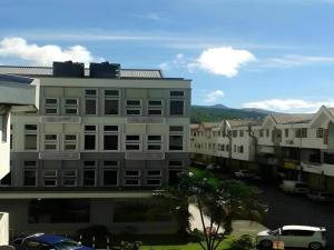 a tall building with cars parked in a parking lot at Hotel Puri 36 in Inanam