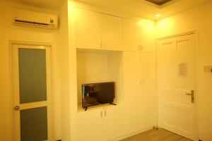 a room with a tv on a wall with white cabinets at New Hotel & Apartment in Thu Dau Mot