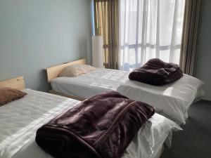 Habitación con 2 camas con mantas marrones. en Katsuura Seaside Hotel, en Nachikatsuura