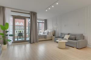 a white living room with a couch and a bed at Waterlane Riverside SPA, Pool & Gym by Downtown Apartments in Gdańsk