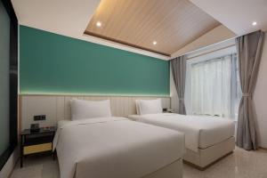 Una habitación de hotel con dos camas y una ventana. en Wanda Yi, Suite Xishuangbanna, en Jinghong