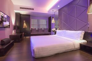 een slaapkamer met een groot bed met een paarse muur bij Orange Hotel Suzhou Emerald Plaza in Suzhou