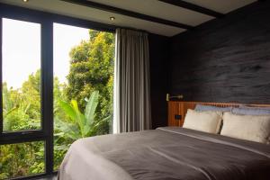 a bedroom with a bed and a large window at Wanagiri Cabin in Gitgit
