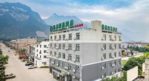 GreenTree Inn Huayin Huashan Town Huashan Scenicspot Express Hotel في Huayin: مبنى أبيض اللون تعلوه لمسات خضراء