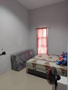 una camera con letto, finestra e ventilatore di Berastagi a Berastagi