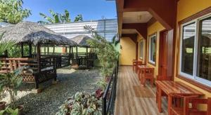 SUMMER WIND PENSION في Puerto Princesa: شرفة منزل مع طاولات وكراسي