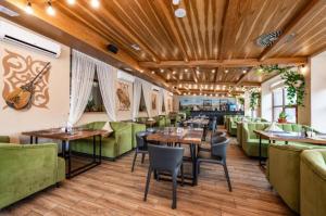 Green Wellness Burabay في بوروفوي: مطعم ذو أثاث أخضر وطاولات وكراسي