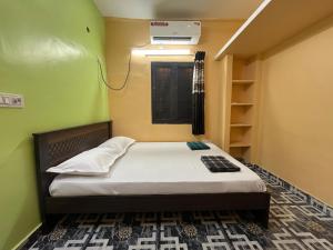 a small bedroom with a bed and a green wall at GYANi 1 in Tiruvannāmalai