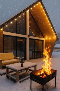 a fire pit in front of a house in the snow at Borjomi inn Cottages in Borjomi