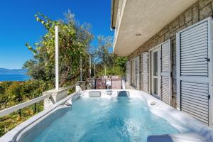 a bath tub sitting on the side of a house at Apartment Paris with jacuzzi and sea view in Šmrika