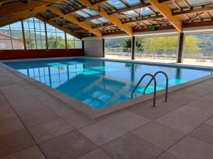 a large swimming pool with blue water in a building at L'Erable T2 climatisé in Trébas