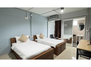 una camera con 2 letti, una scrivania e uno specchio di Collection O Mahidol Road a Chiang Mai