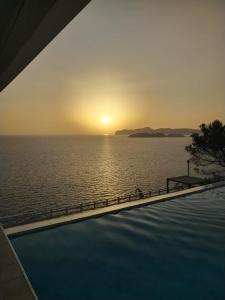 a pool with a view of the ocean at sunset at Exclusive Seafront Villa,Private Pool,Gym,BBQ in El Toro