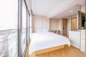 a bedroom with a large white bed and a window at Prime Pazhou Aparthotel - Pazhou Station Line 8 and 11 - Steps away from Canton Exhibition Center in Guangzhou