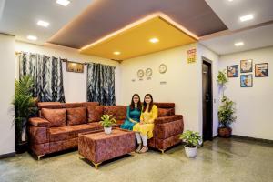 two women sitting on a couch in a waiting room at FabHotel Tap Inn in Bengaluru