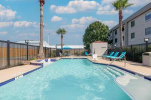 una piscina con sillas y palmeras en Hampton Inn Houston-Deer Park Ship Area, en Deer Park