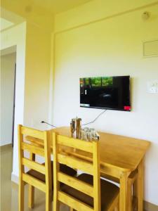 mesa de comedor con 2 sillas y TV en la pared en Dodamarg Heights, en Dodamarg