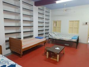 una camera con due letti, un tavolo e scaffali di Adb's Kuzhlam Rooms a Tiruchchirāppalli