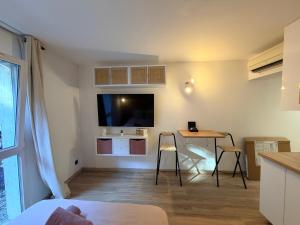 Una sala de estar con una mesa y un televisor en la pared. en Le Clos d'AIX studio 1, en Aix-en-Provence