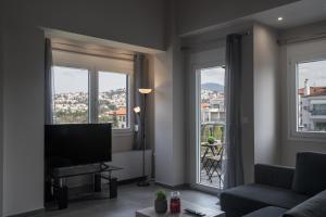 a living room with a television and two large windows at Panorama Sunvilles Apartment 9 in Thessaloniki
