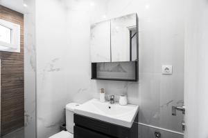 a white bathroom with a sink and a mirror at Panorama Sunvilles Apartment 9 in Thessaloniki