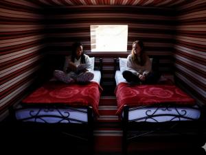 Golden Day Bedouin Camp في وادي رم: كانتا جالستين على السرير في غرفة