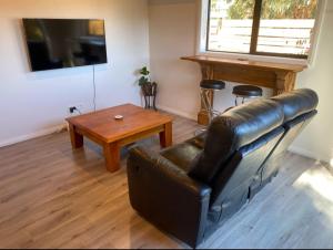 a living room with a leather couch and a table at Birchwood in Wanaka
