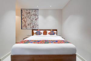 a bedroom with a large white bed with colorful sheets at FabHotel Eraya in Varanasi +15 photos