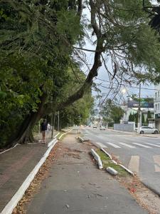 eine Person, die einen Bürgersteig neben einem Baum entlang läuft in der Unterkunft Apart CENTRO in Tubarão + 1 Foto