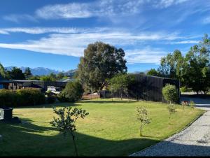 a green yard with trees and a fence at Birchwood in Wanaka