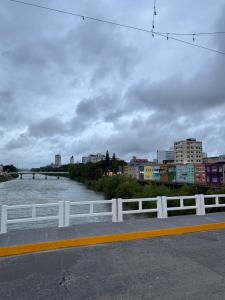 ein Fluss mit einem weißen Zaun neben einer Stadt in der Unterkunft Apart CENTRO in Tubarão