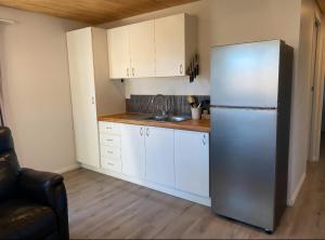 a kitchen with a stainless steel refrigerator and white cabinets at Birchwood in Wanaka