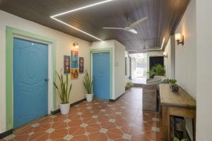 Un pasillo con puertas azules y plantas en una habitación. en FabHotel Golden Nest Deluxe - Nr Calangute Beach, en Old Goa