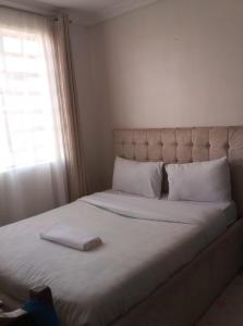 a large bed with a white headboard and a window at Victorian Haven in Eldoret