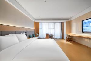 ein Hotelzimmer mit einem großen Bett und einem Flachbildfernseher in der Unterkunft JI Hotel Chongqing Yufu Industrial Park TuoXinXing Times in Chongqing