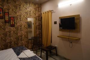 a bedroom with a bed and a tv on a wall at Hotel Kasol Heritage in Lucknow