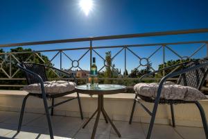 a table and chairs on a balcony with a bottle of wine at Kastalia Springs 3bd VIilla in Peiya by VICHY Holidays in Peyia