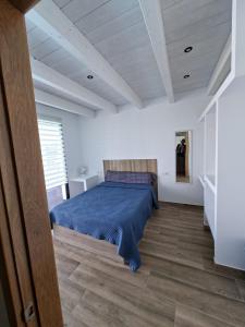 una camera da letto con un letto blu in una stanza bianca di Chalet Los Molinos a La Oliva Altre 14 foto