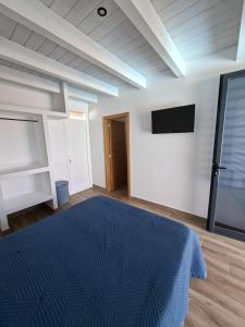 una camera da letto con un letto blu e una TV a schermo piatto di Chalet Los Molinos a La Oliva