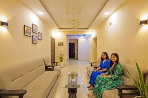 two women sitting on couches in a living room at FabHotel Club Metro in Nagpur