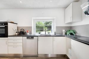 a white kitchen with white cabinets and a window at Villa Surrounded By Nature in Vissenbjerg