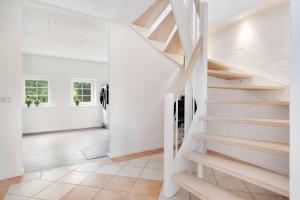 a white staircase in a living room with white walls at Villa Surrounded By Nature in Vissenbjerg +19 photos