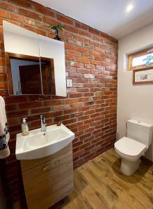 a bathroom with a white sink and a brick wall at Sodyba Viltis in Bikavėnai +33 photos