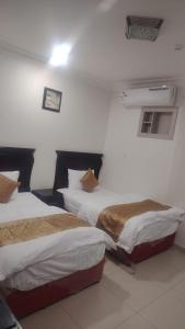 two beds in a room with white walls at أرض الذهب للشقق المخدومة القويعية in Al Quway‘īyah