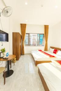 a hotel room with two beds and a desk and a tv at Khách sạn Đức Phúc in Dồng Văn