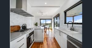 una cucina con ripiani bianchi e una grande finestra di Abode On North Ridge a Cooma