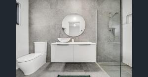 un bagno con un water, un lavandino e uno specchio di Abode On North Ridge a Cooma Altre 4 foto