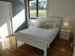 una camera da letto con un letto bianco con due lampade di Abode On North Ridge a Cooma