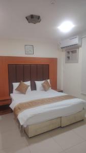 a bedroom with a large bed with a wooden headboard at أرض الذهب للشقق المخدومة القويعية in Al Quway‘īyah