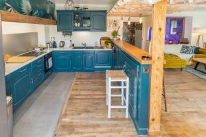 L'Estagnole pour 2 personnes, jacuzzi, hammam في إستين: مطبخ مع دواليب زرقاء وارضية خشبية